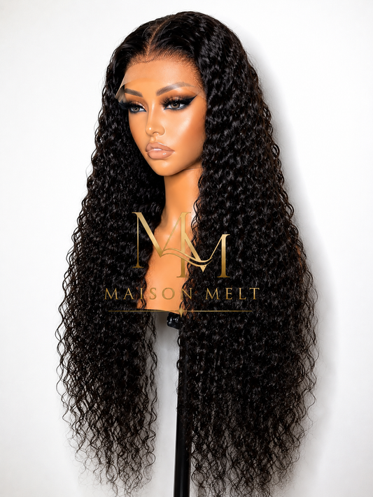 Mannequin head with long, wavy black wig on a white background, featuring the Maison Melt logo.